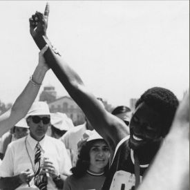 Black and white image of someone holding a male athlete's arm in the air as he forms a 