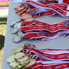 Gold, silver, and bronze medals with red Special Olympics ribbons attached placed on a table.