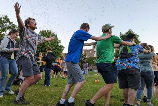 People playing outside on the grass with bubbles.