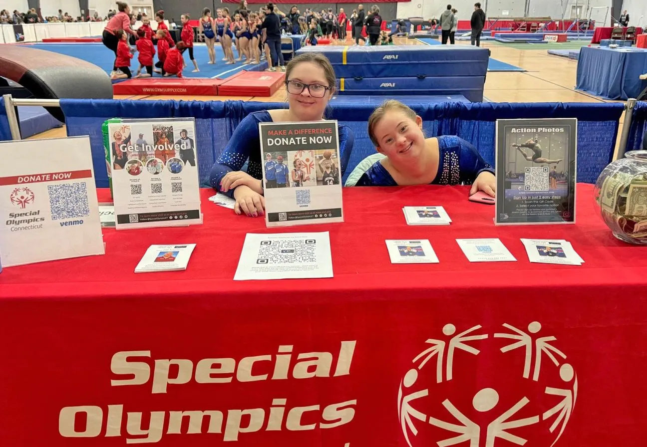 Young man in blue tshirt holding a Penguin Plunge plaque. 