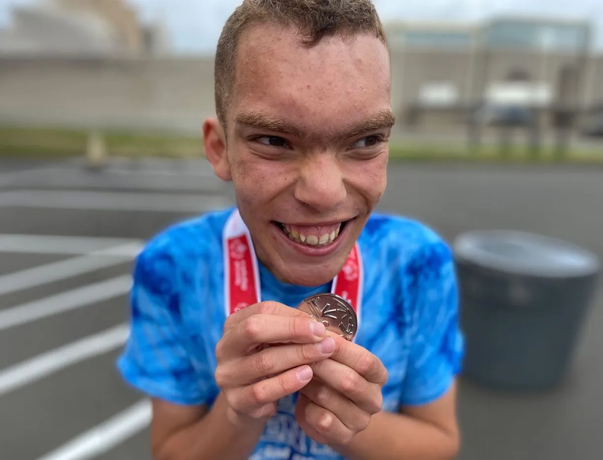 Athlete on a bike wearing an orange shirt near green trees.