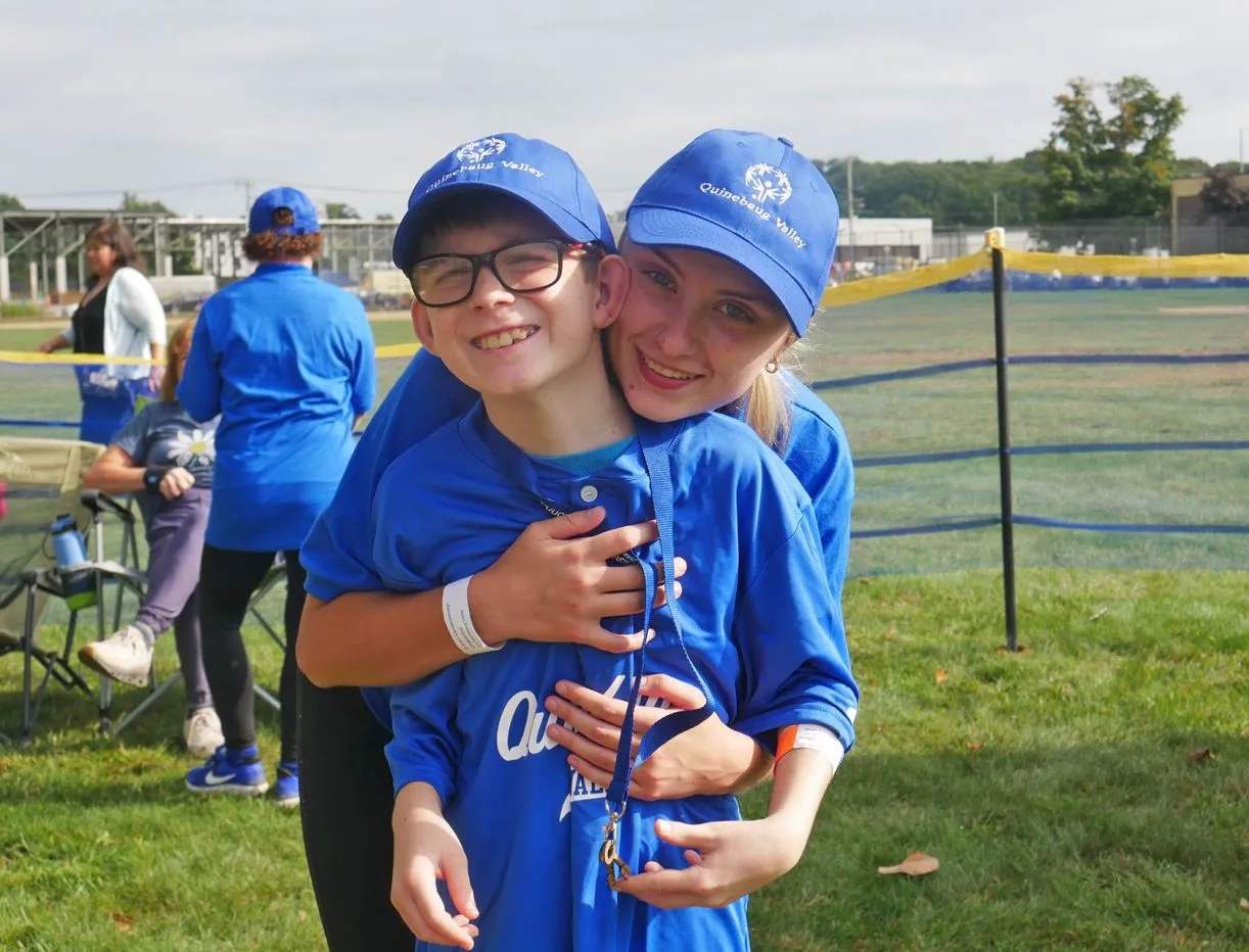 Athletes and coach wearing neon orange shirts standing in a gymnasium.