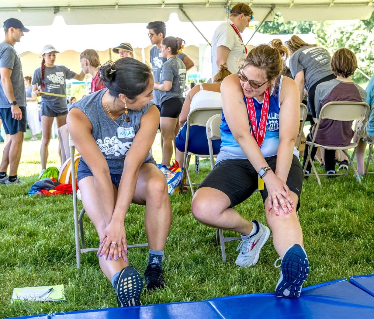 Athlete wearing a grey t-shirt and face mask getting his height and weight measured.