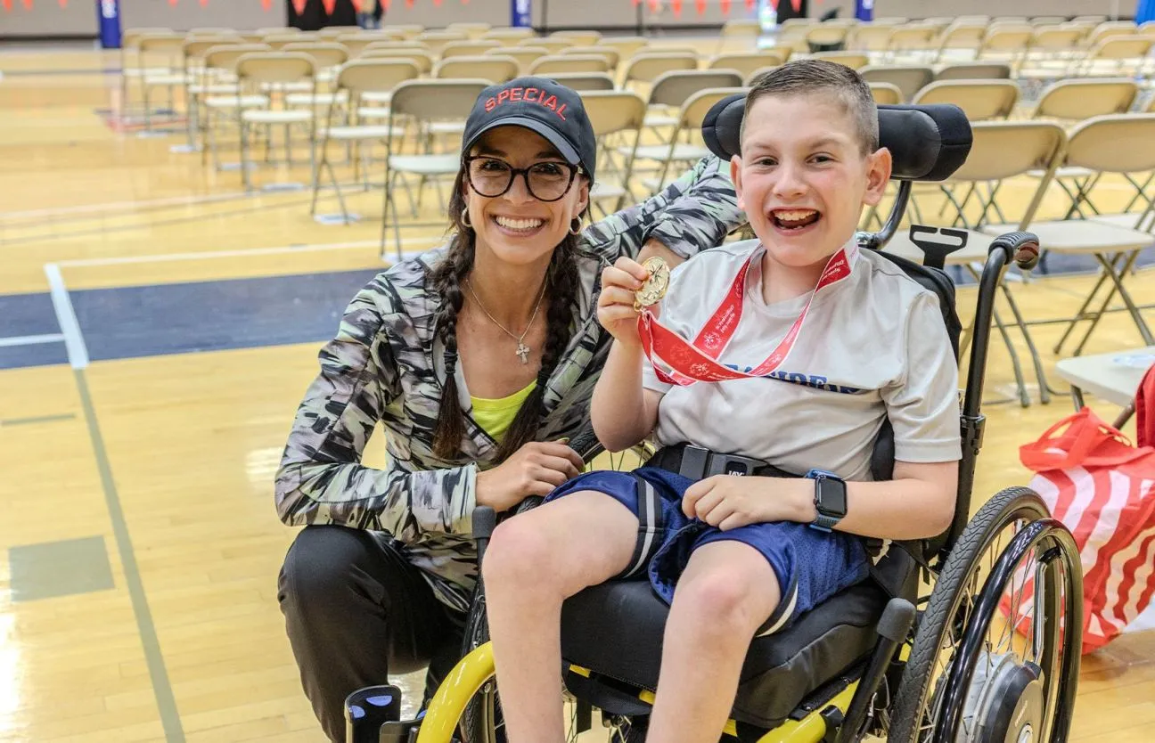 Two athletes standing with a partner outside in the snow wearing skiing attire.
