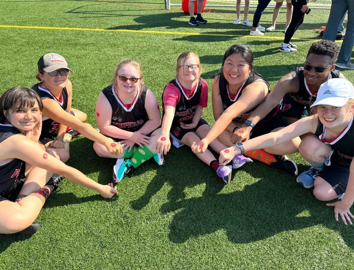 Group of athletes on an outdoor track holding up a banner that reads Broadview United Unified Sports.