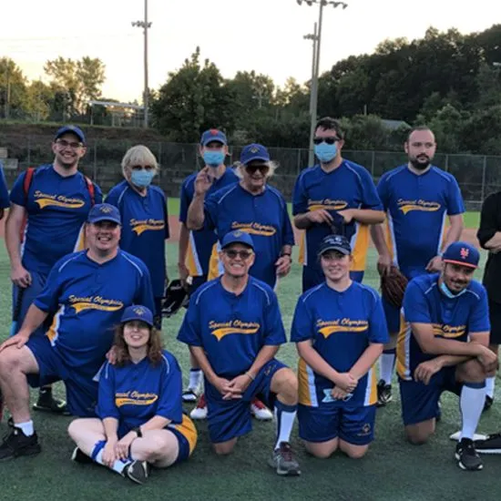 Unified softball team photo of athletes wearing blue, gold and white jerseys that say 
